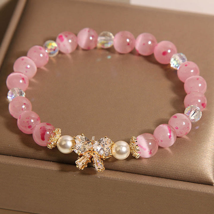 Braccialetto di supporto con fiocco e rosetta, in perle occhio di gatto rosa e fiori di ciliegio Buddha Stones